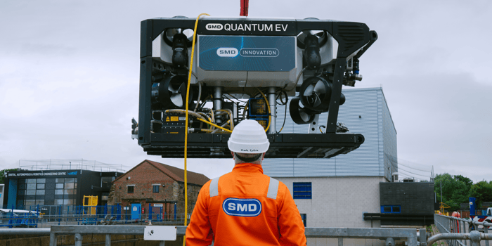 SMD subsea vehicle suspended in the air with an SMD engineer looking on